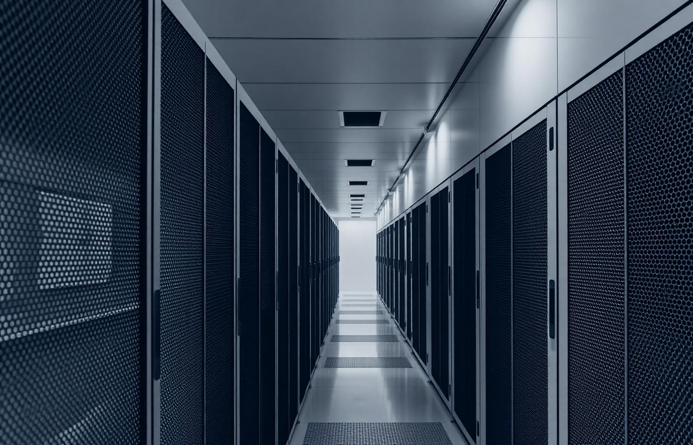 Corridor of server racks in a data centre, viewed in monochrome